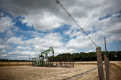 Oil edges down on easing Middle East risks but gains for a second month